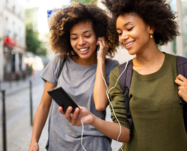 Two_women_happily_share_an_audiobook_as_they_walk_down_the_street (1)