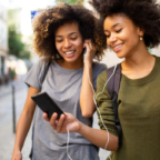 Two_women_happily_share_an_audiobook_as_they_walk_down_the_street (1)